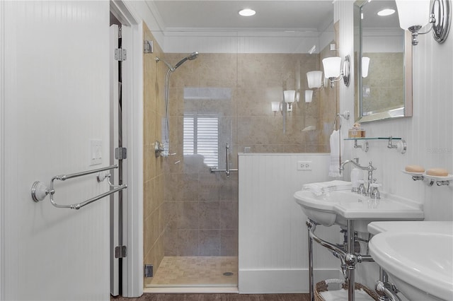 bathroom with dual sinks, ornamental molding, and walk in shower