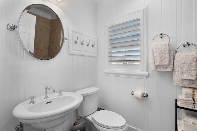 bathroom featuring toilet, ornamental molding, and sink