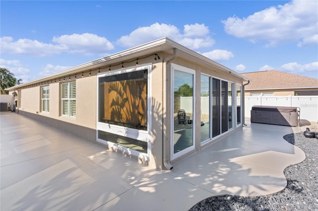 view of property exterior featuring central AC unit, a patio, and a hot tub