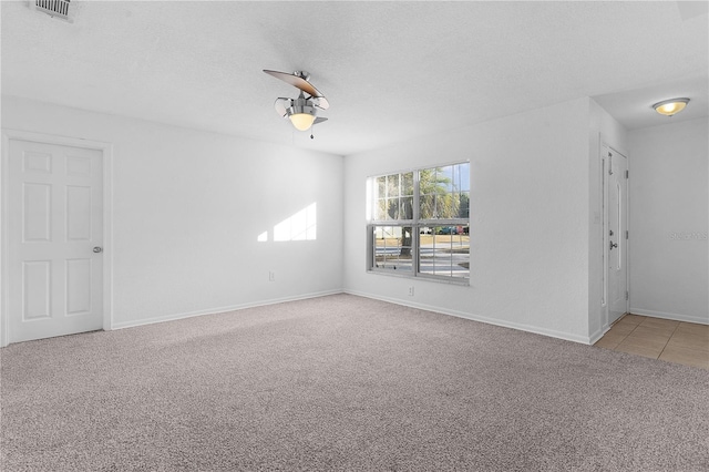 spare room featuring light colored carpet and a textured ceiling