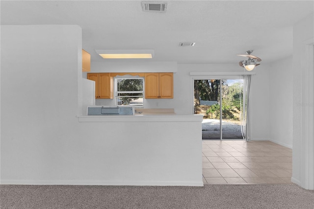 kitchen with light brown cabinets, light colored carpet, and kitchen peninsula