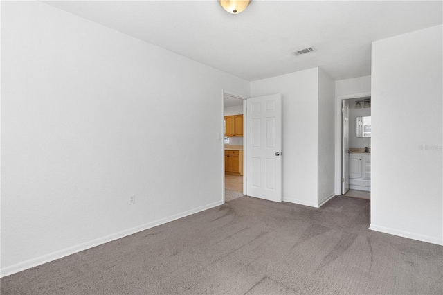 unfurnished bedroom with dark colored carpet and connected bathroom