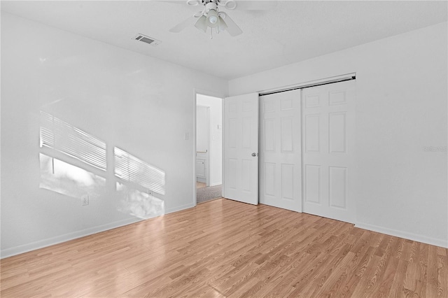 unfurnished bedroom featuring a closet, light hardwood / wood-style floors, and ceiling fan