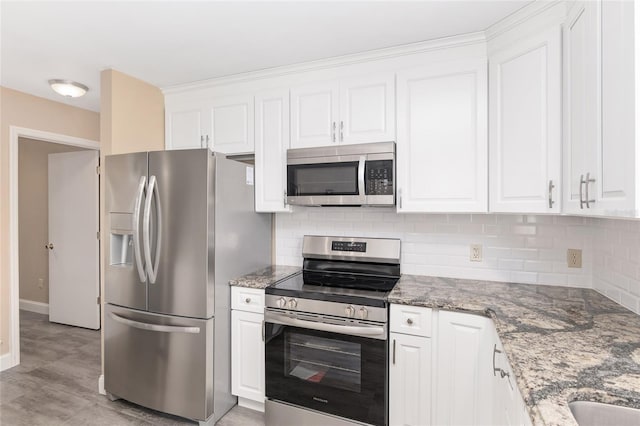 kitchen featuring white cabinets, backsplash, stainless steel appliances, and dark stone countertops