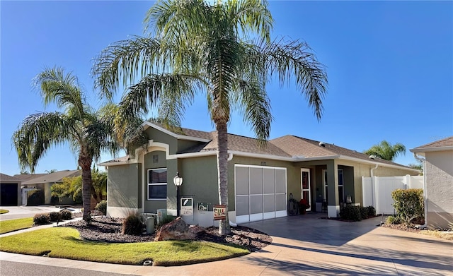 ranch-style home with a garage, fence, concrete driveway, and stucco siding