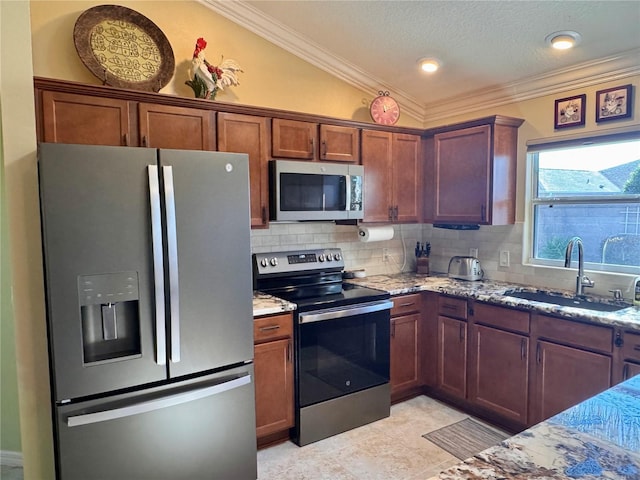 kitchen with light stone counters, sink, stainless steel appliances, and vaulted ceiling