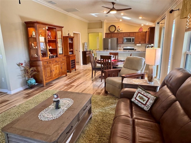 living room featuring ceiling fan, light hardwood / wood-style flooring, vaulted ceiling, and ornamental molding