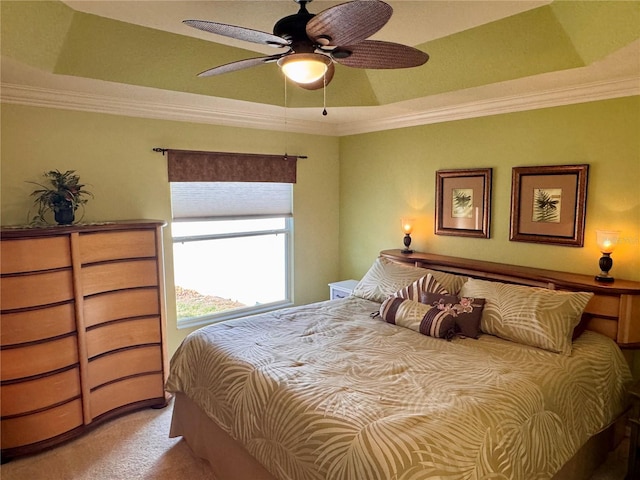 carpeted bedroom with ceiling fan, crown molding, and a tray ceiling