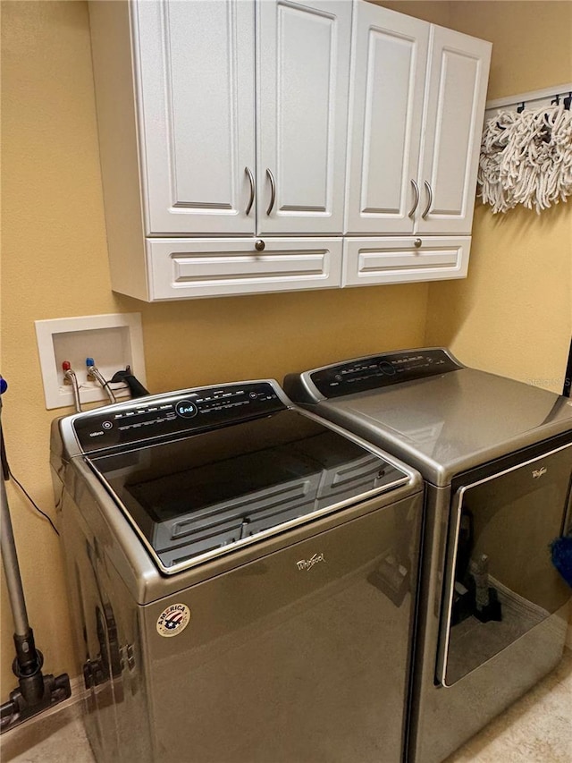 laundry area with washer and dryer and cabinets