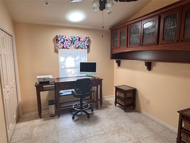 tiled office space featuring a textured ceiling and ceiling fan