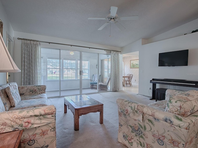 carpeted living room with lofted ceiling, ceiling fan, and a textured ceiling