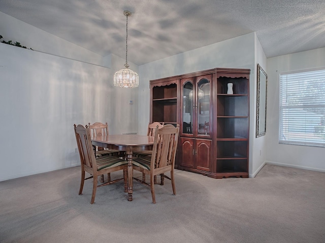 dining area with light carpet, lofted ceiling, a textured ceiling, and an inviting chandelier