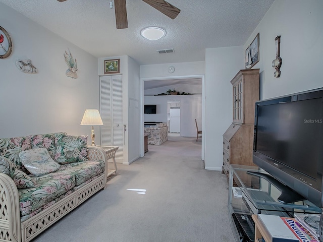 carpeted living room with ceiling fan and a textured ceiling