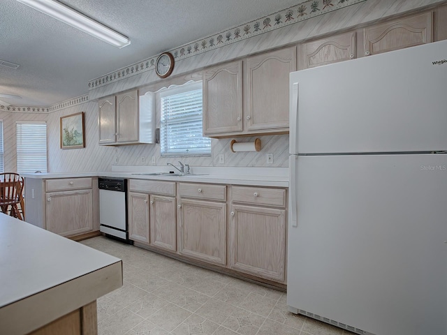 kitchen featuring dishwashing machine, sink, a textured ceiling, light brown cabinetry, and white fridge