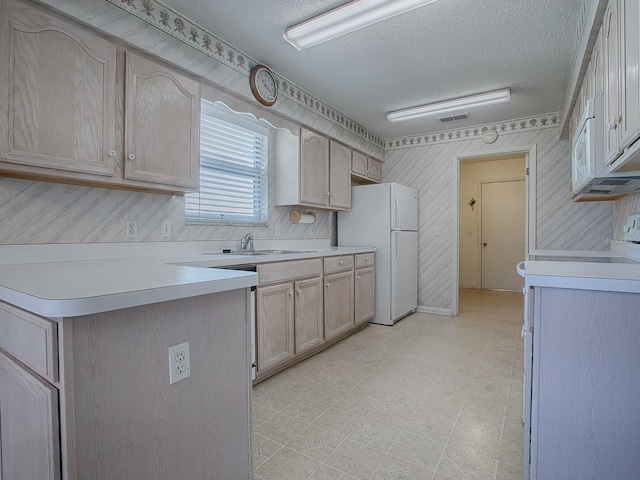 kitchen featuring sink, range, light brown cabinets, a textured ceiling, and white fridge