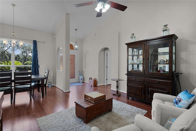 living room with vaulted ceiling, ceiling fan with notable chandelier, and dark hardwood / wood-style flooring