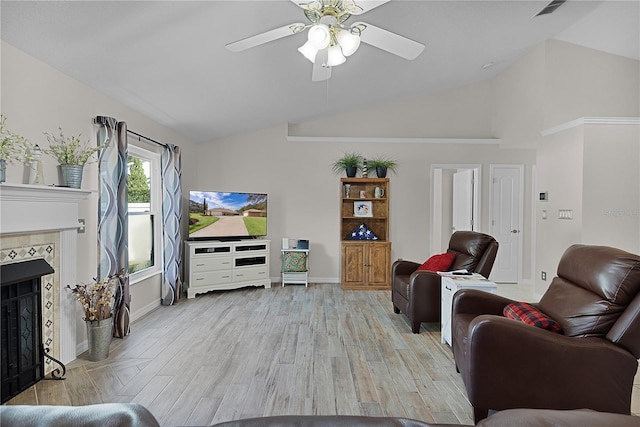 living room featuring ceiling fan, a high end fireplace, vaulted ceiling, and light wood-type flooring