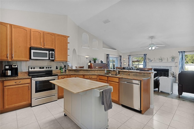 kitchen with light tile patterned flooring, sink, a center island, ceiling fan, and stainless steel appliances