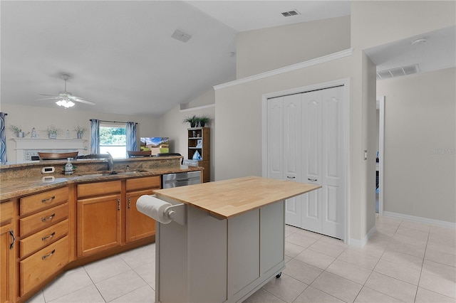 kitchen with lofted ceiling, butcher block counters, sink, a center island, and light tile patterned floors