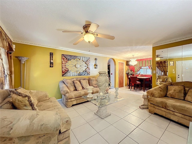 living room with tile patterned flooring, ceiling fan, ornamental molding, and a textured ceiling