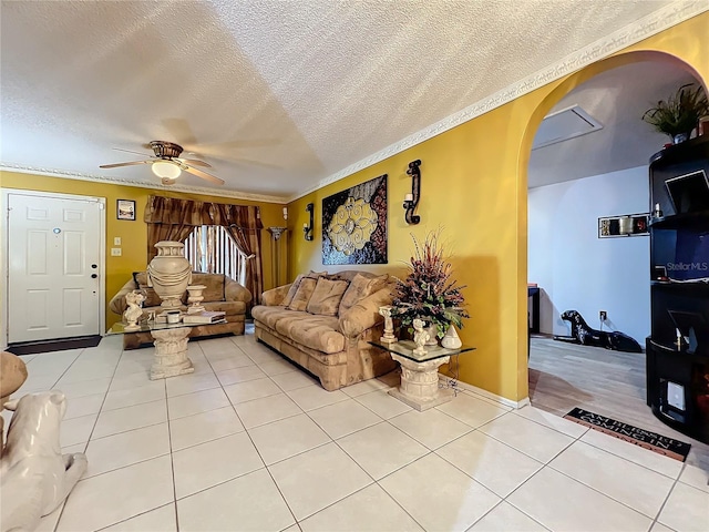 tiled living room featuring ceiling fan, ornamental molding, and a textured ceiling