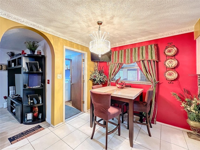 dining room with tile patterned floors, ornamental molding, a textured ceiling, and an inviting chandelier