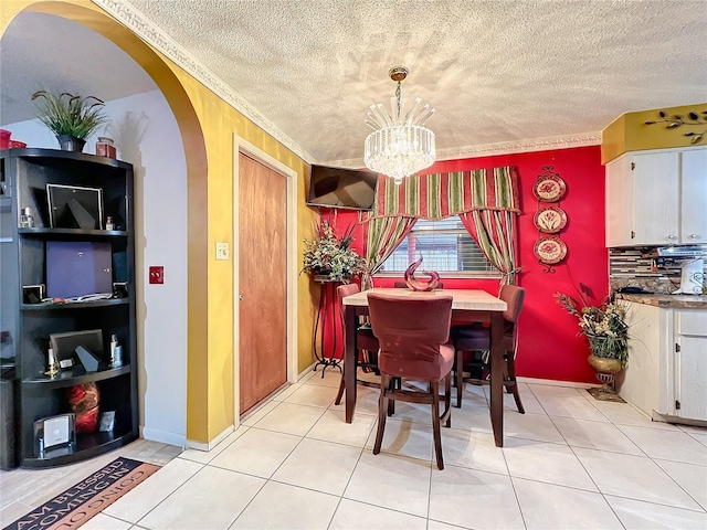 tiled dining space with a chandelier, a textured ceiling, and ornamental molding