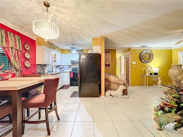 kitchen with white cabinetry, crown molding, pendant lighting, black appliances, and ceiling fan with notable chandelier