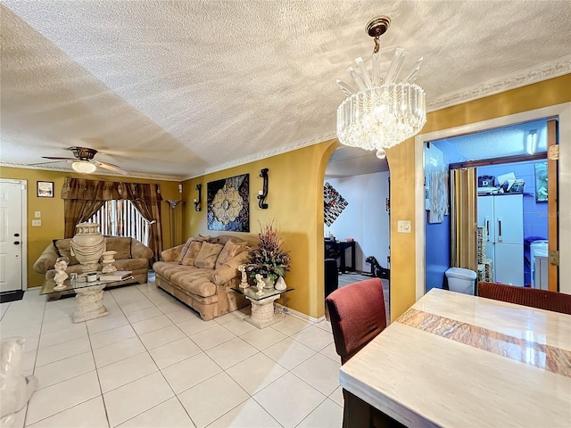 living room with tile patterned floors, ceiling fan with notable chandelier, ornamental molding, and a textured ceiling