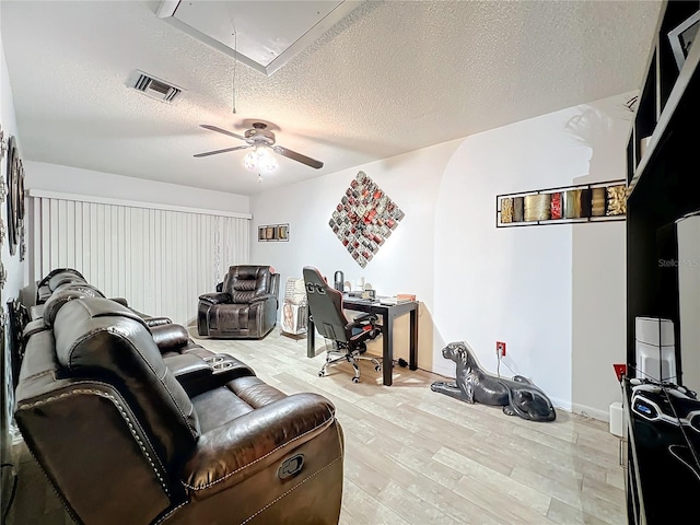 living room with ceiling fan, a textured ceiling, and light wood-type flooring