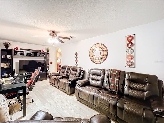 living room with ceiling fan, a textured ceiling, and hardwood / wood-style flooring