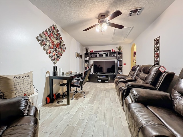 living room with hardwood / wood-style floors, ceiling fan, and a textured ceiling