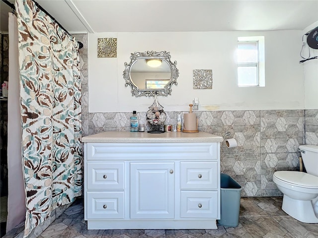 bathroom featuring vanity, toilet, and tile walls