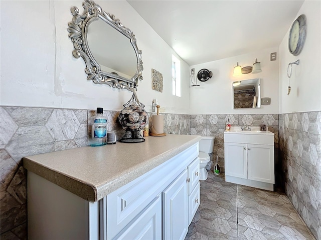 bathroom with vanity, tile walls, and toilet