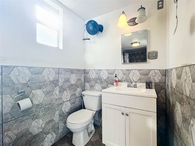 bathroom with vanity, toilet, and tile walls