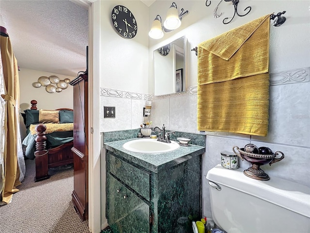 bathroom featuring a textured ceiling, vanity, tile walls, and toilet