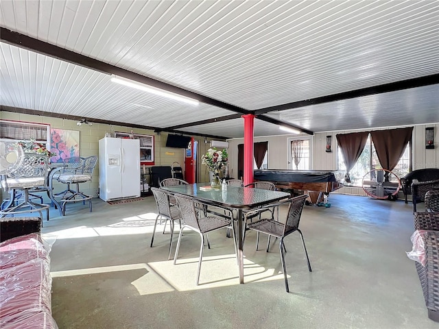 dining room with beam ceiling, concrete floors, and billiards