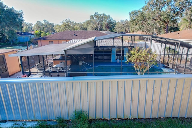 rear view of house with glass enclosure, a patio area, and a swimming pool