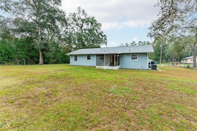 rear view of property featuring a lawn, central air condition unit, and a sunroom