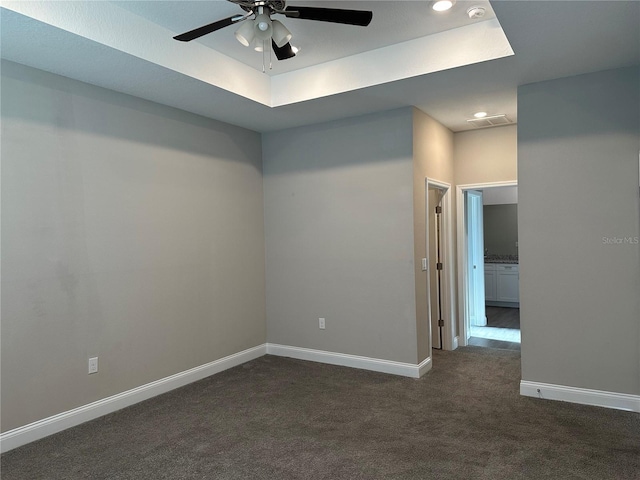 carpeted spare room with ceiling fan and a tray ceiling