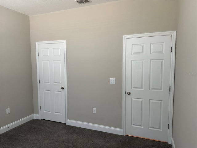 unfurnished bedroom with dark colored carpet