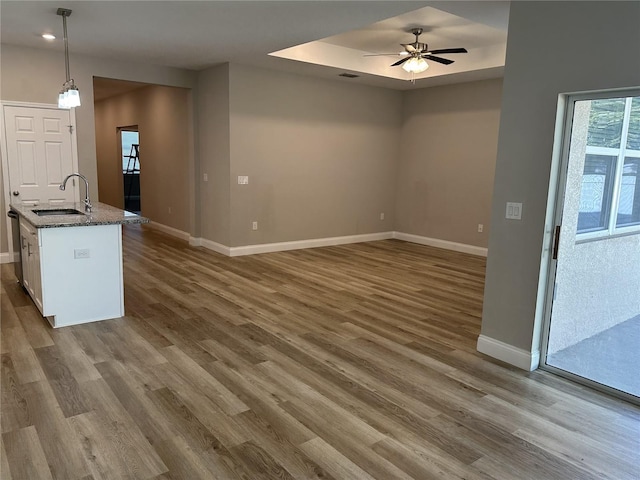 kitchen with sink, stone counters, pendant lighting, ceiling fan, and hardwood / wood-style floors