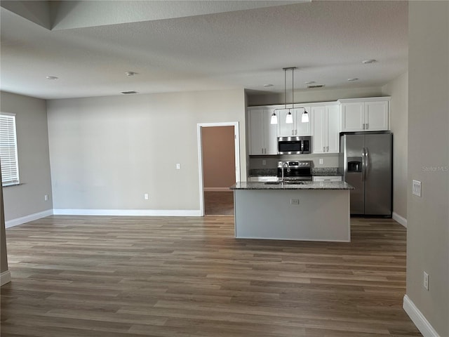 kitchen with pendant lighting, sink, a kitchen island with sink, stainless steel appliances, and white cabinets