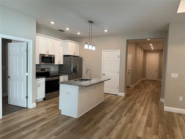 kitchen with an island with sink, white cabinetry, sink, hanging light fixtures, and stainless steel appliances