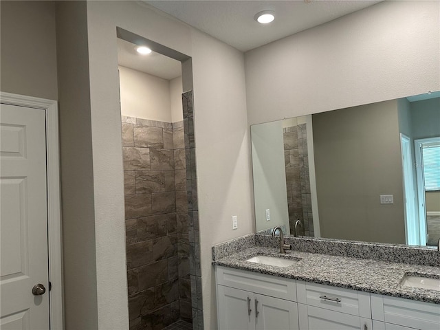 bathroom featuring tiled shower and vanity