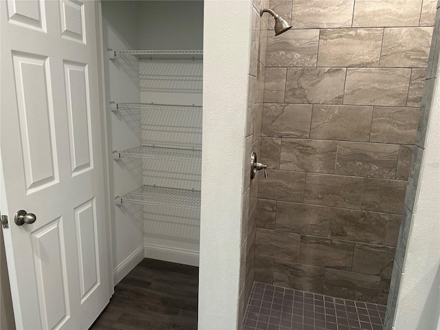 bathroom featuring hardwood / wood-style flooring and a tile shower