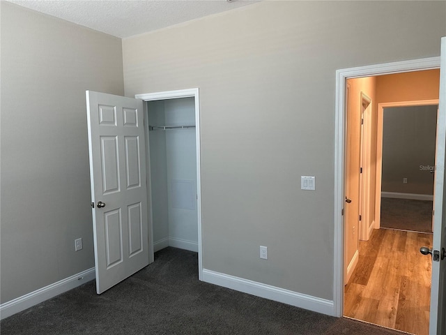 unfurnished bedroom with dark carpet and a closet