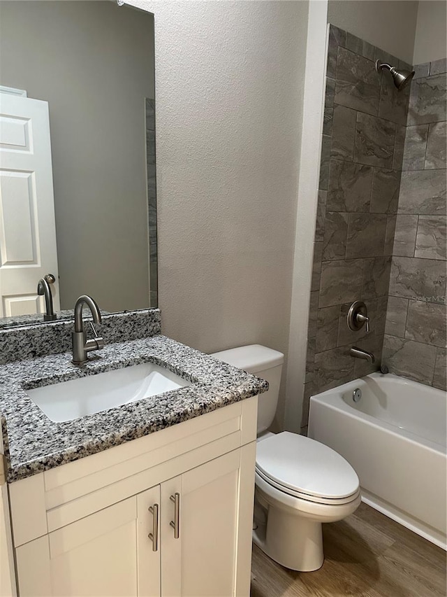 full bathroom featuring vanity, toilet, tiled shower / bath combo, and hardwood / wood-style floors