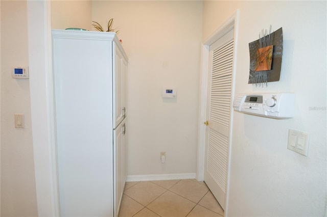 clothes washing area featuring light tile patterned flooring and cabinets