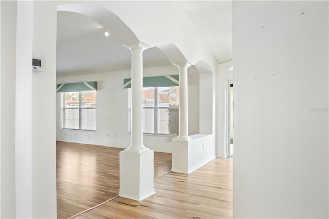 interior space with light hardwood / wood-style floors and ornate columns